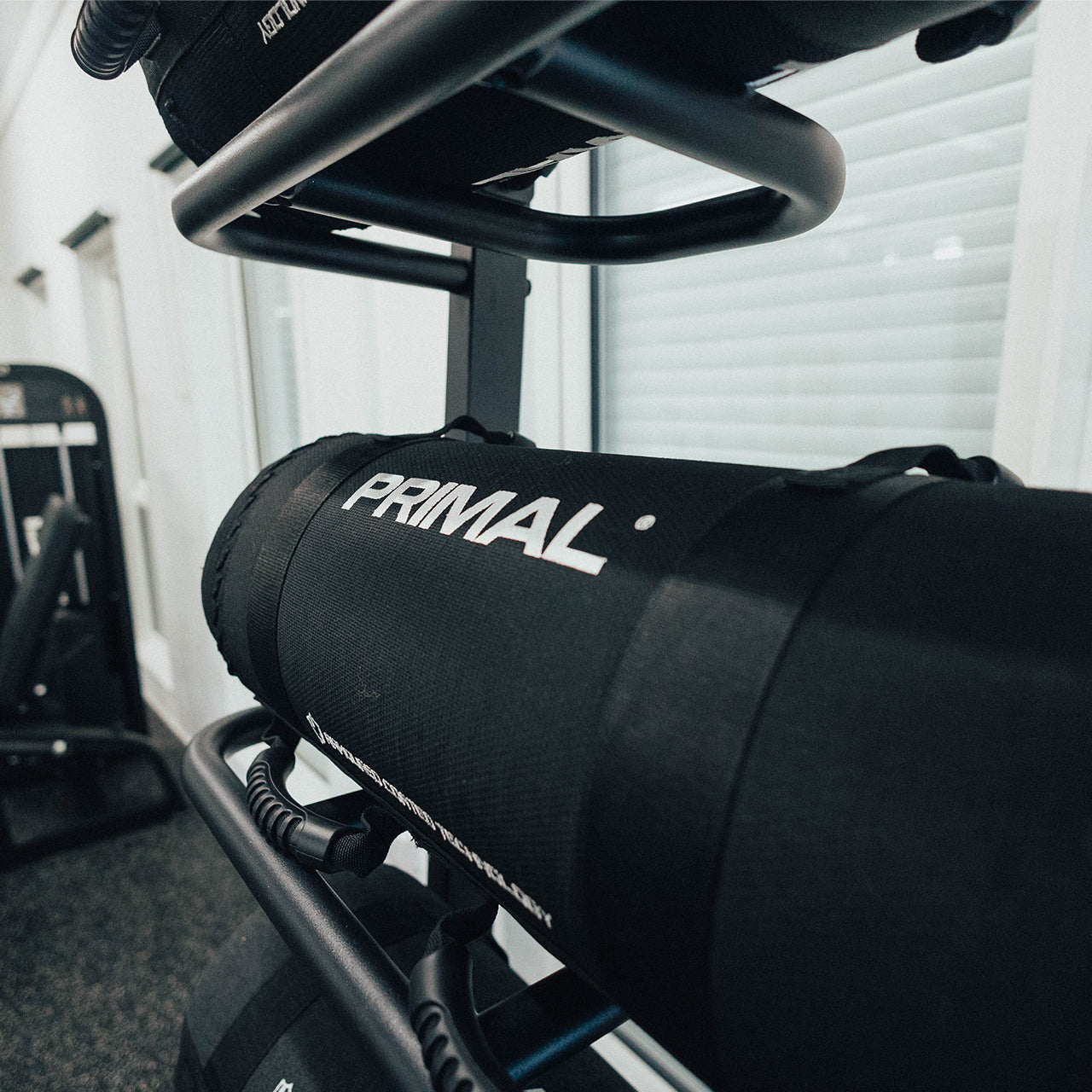 A black competition style sandbag stored on a free standing storage rack.