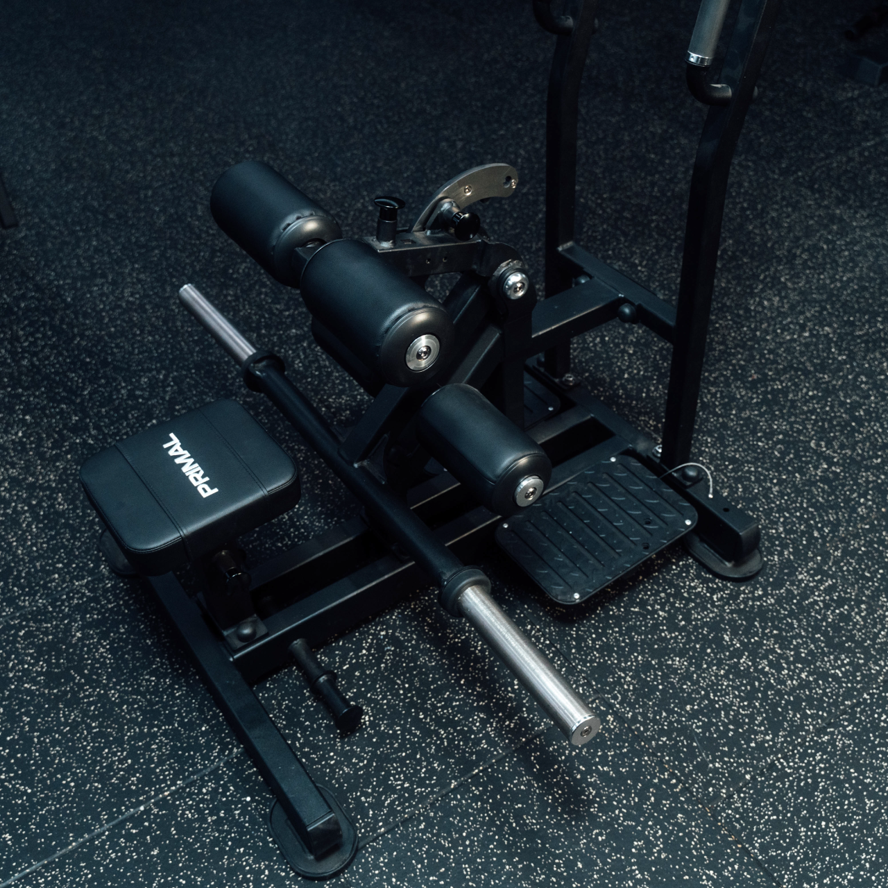 View from above of plate-loaded standing hip thrust machine on gym floor.