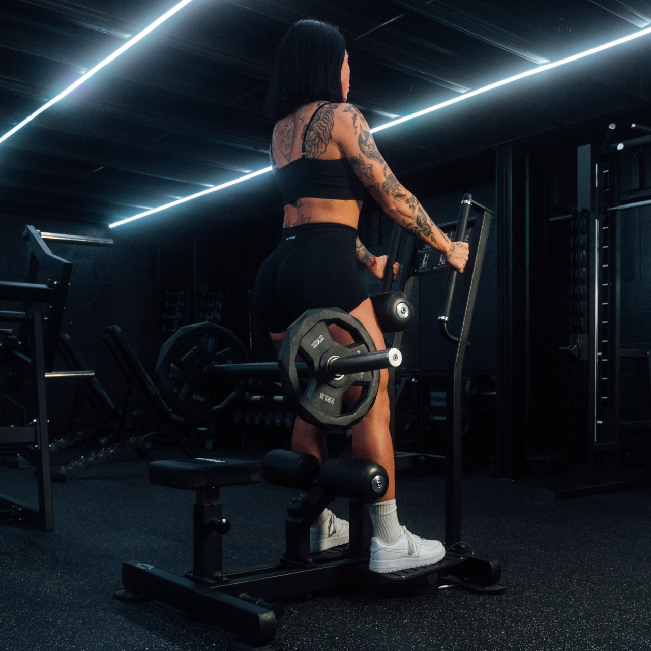 View from back of athlete using standing hip thrust machine with plates loaded onto bullhorns.