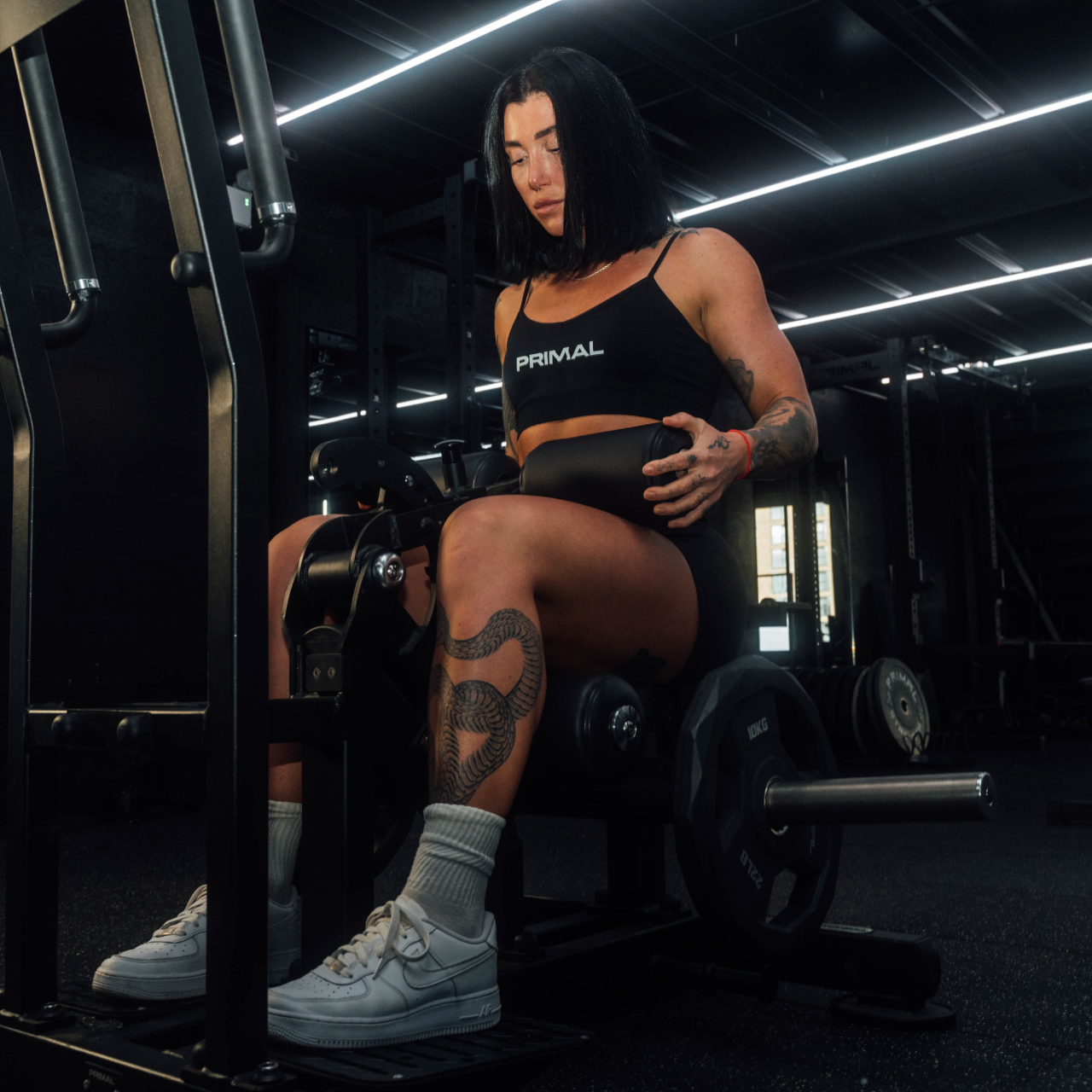 Athlete sitting on plate-loaded standing hip thrust machine.