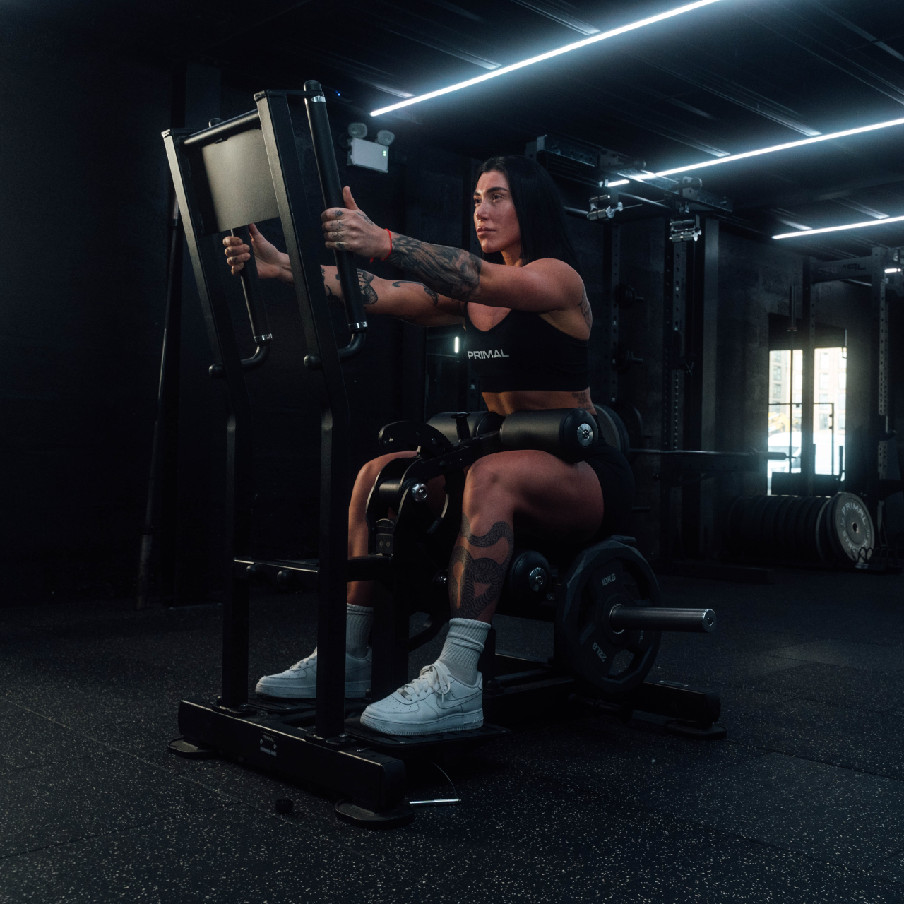 Angled view of athlete using standing hip thrust machine in seated position