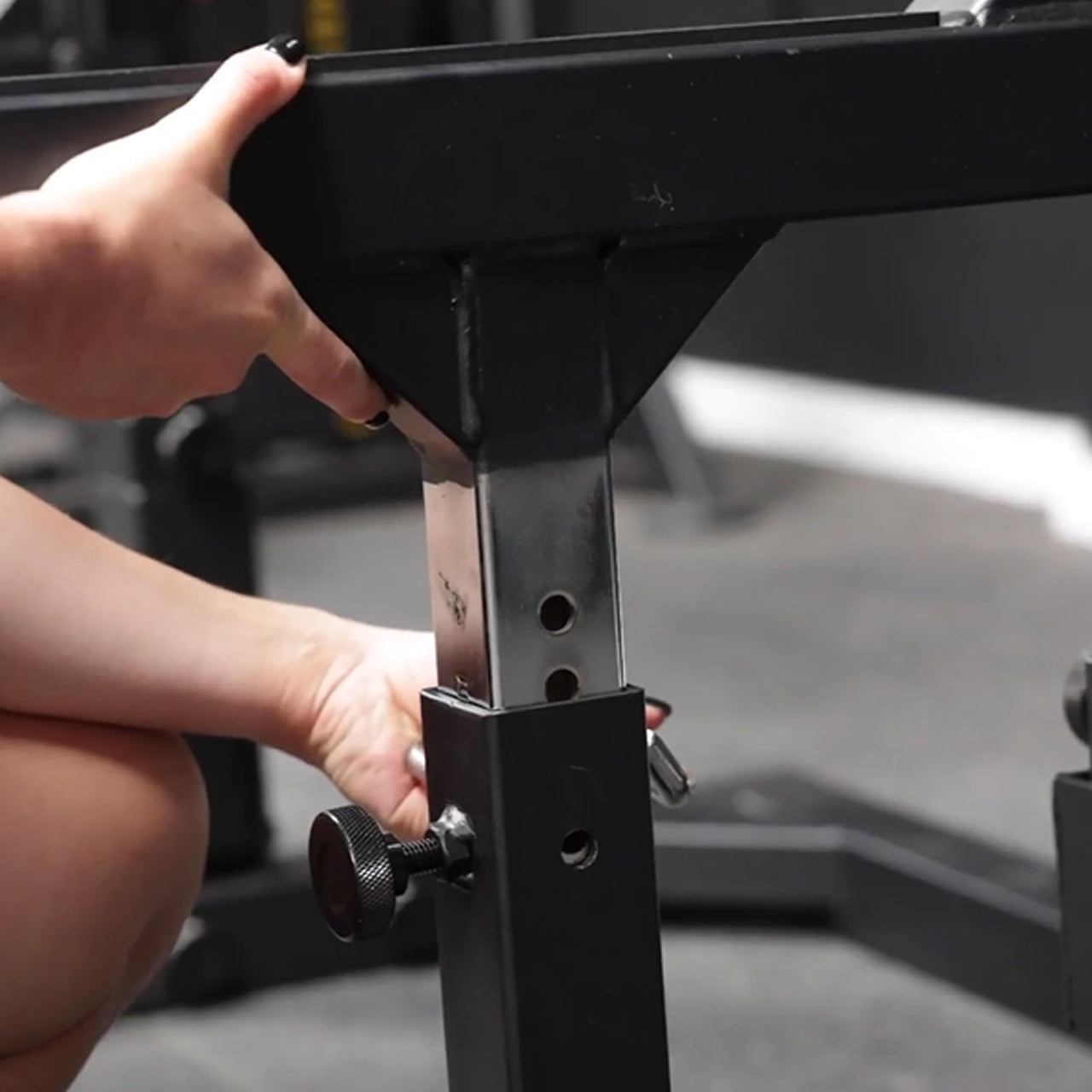 An athlete adjusting the barbell spotter arms on a weight bench.