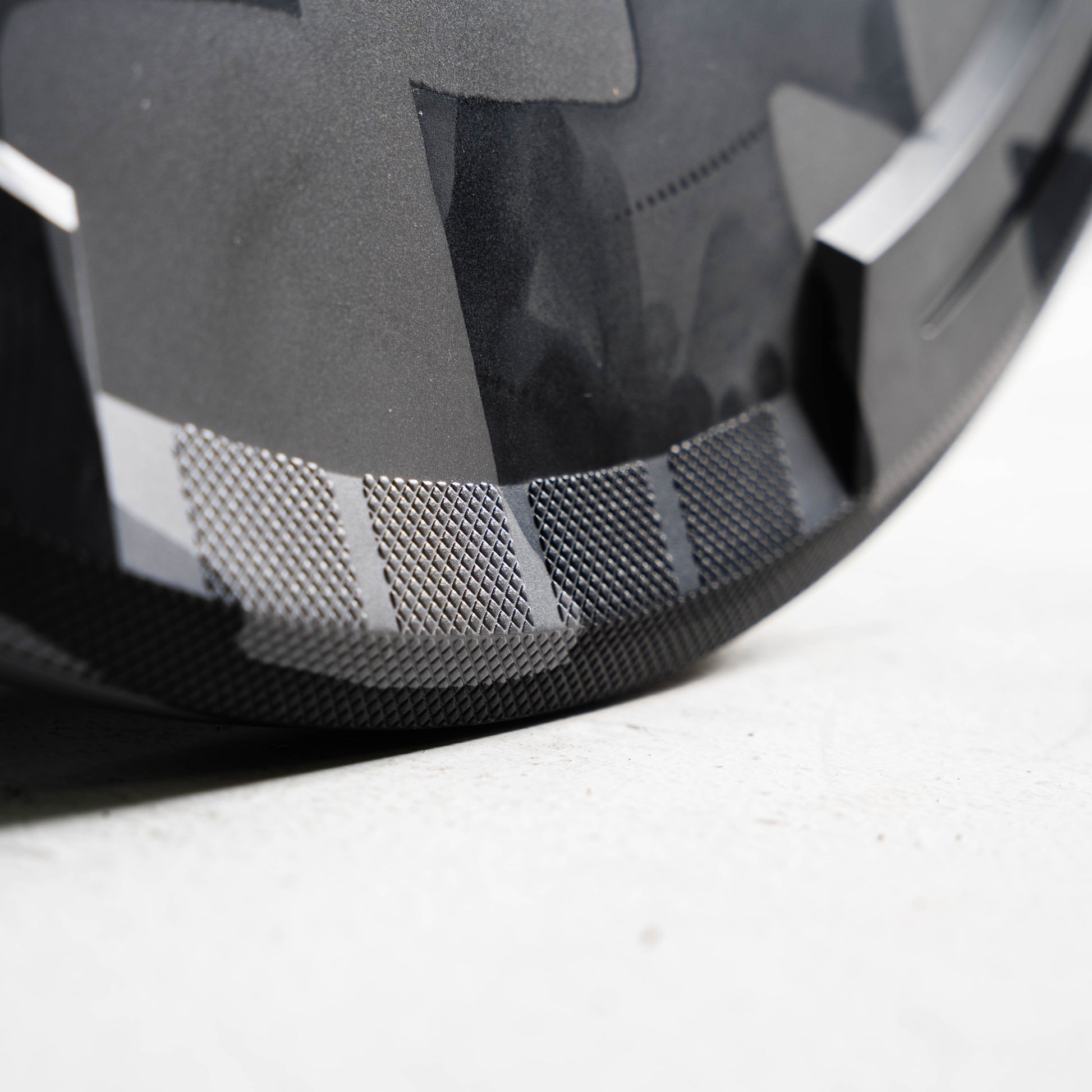 Close-up of a Grey & black bumper plate with a textured pattern on a light gray background