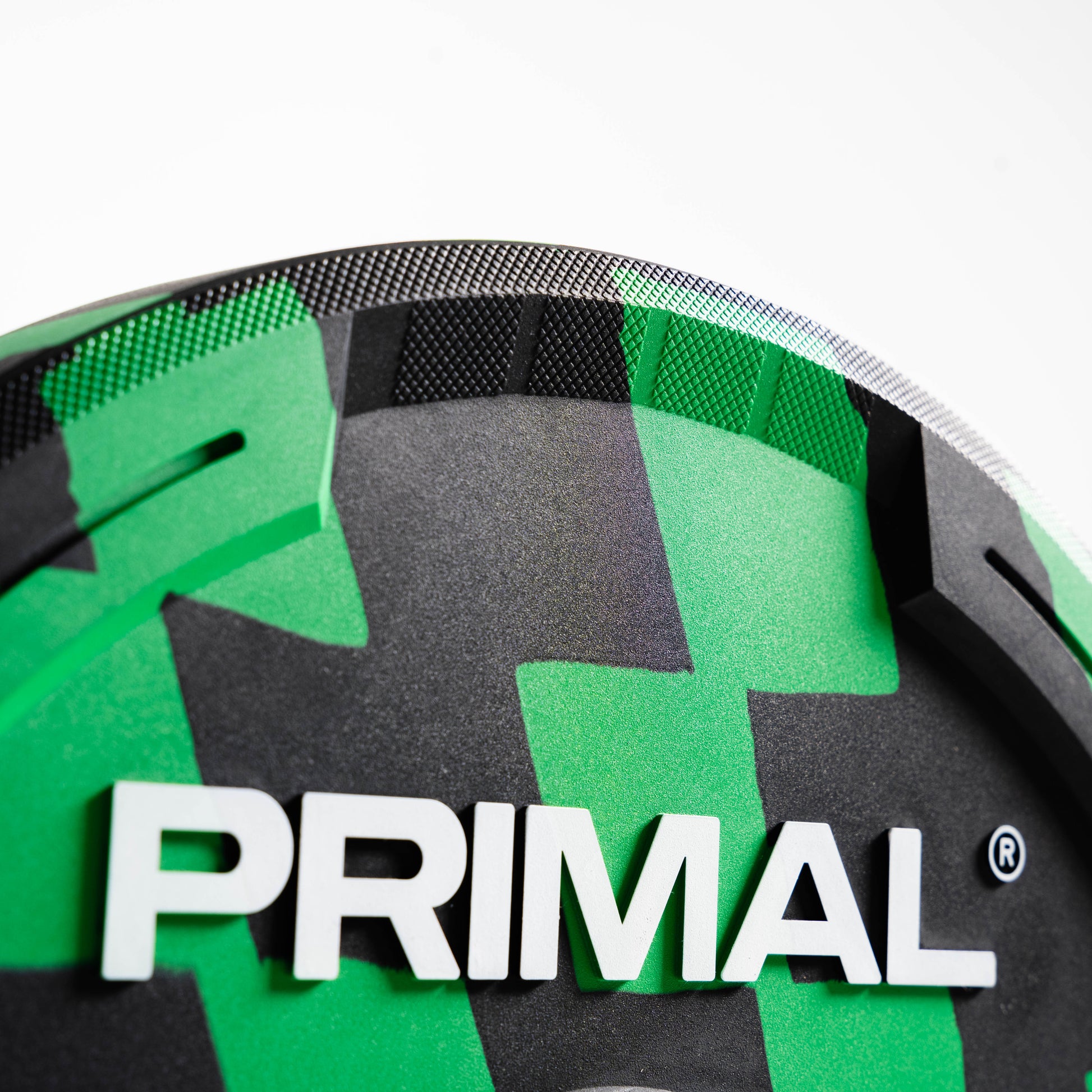 Close-up of a green and black product with 'Primal' branding on a white background