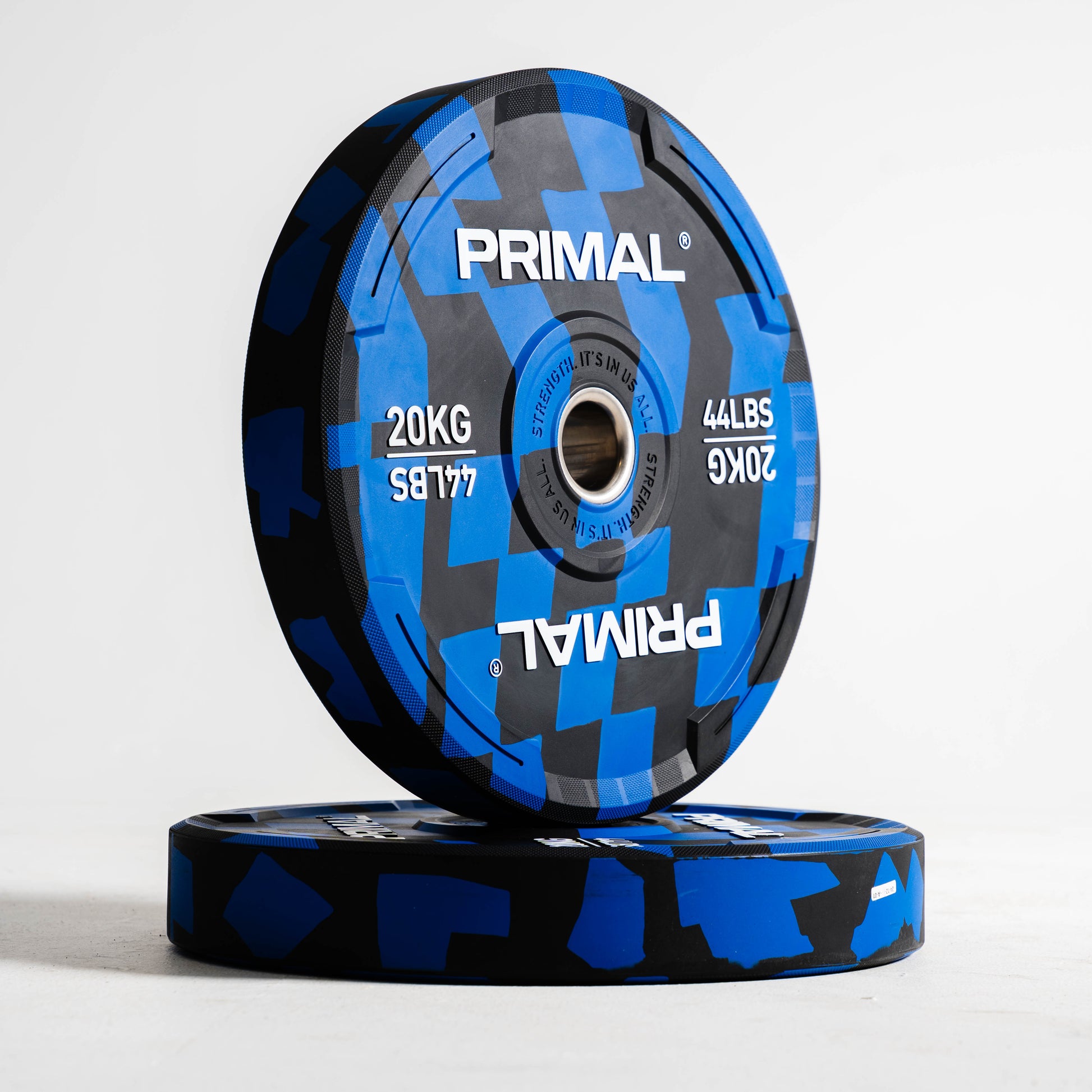 Two blue and black Primal weight plates on a white background
