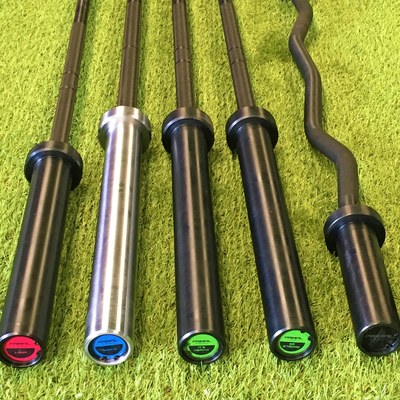 A selection of barbells lying on gym astroturf.