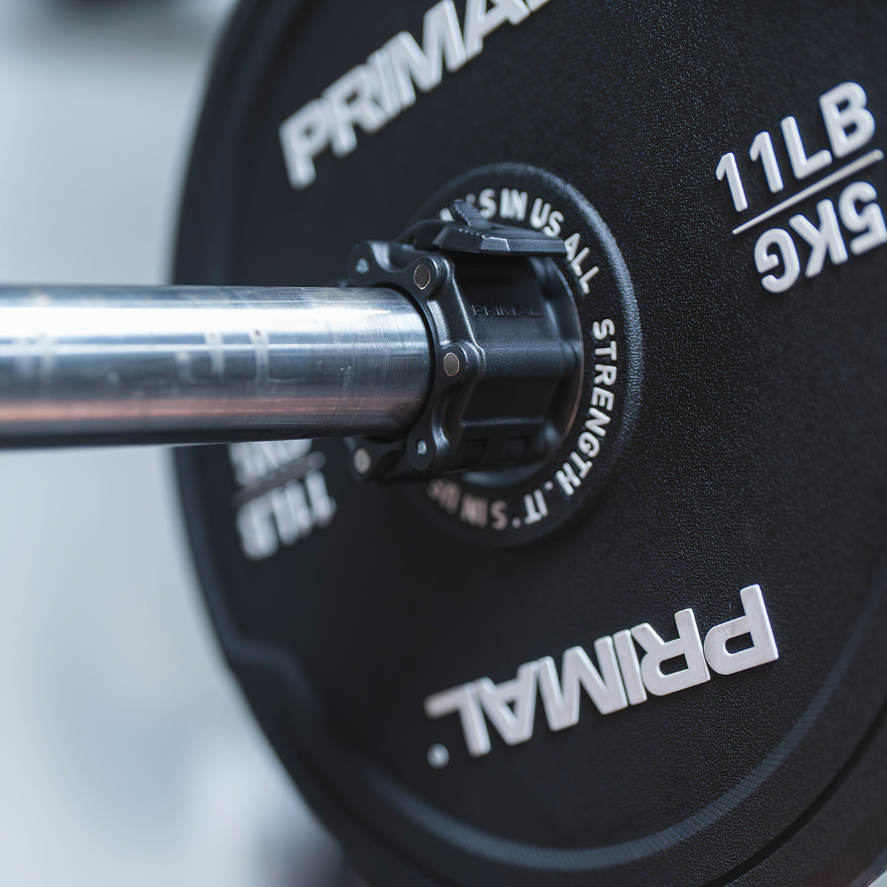 Close up view of a magnetic lockjaw collar securing a bumper plate in place on a barbell.