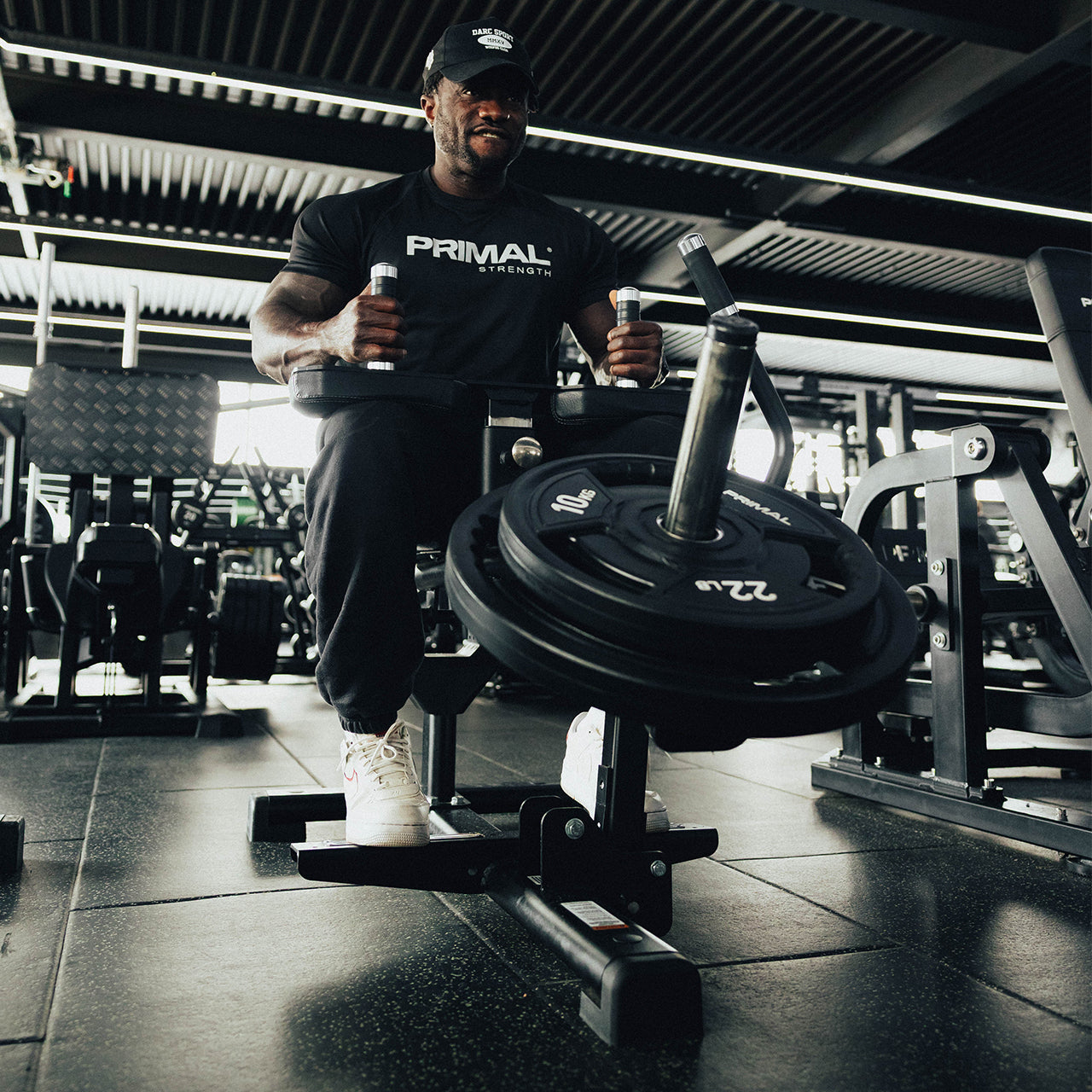 An athlete using a seated calf raise machine loaded with weight discs.