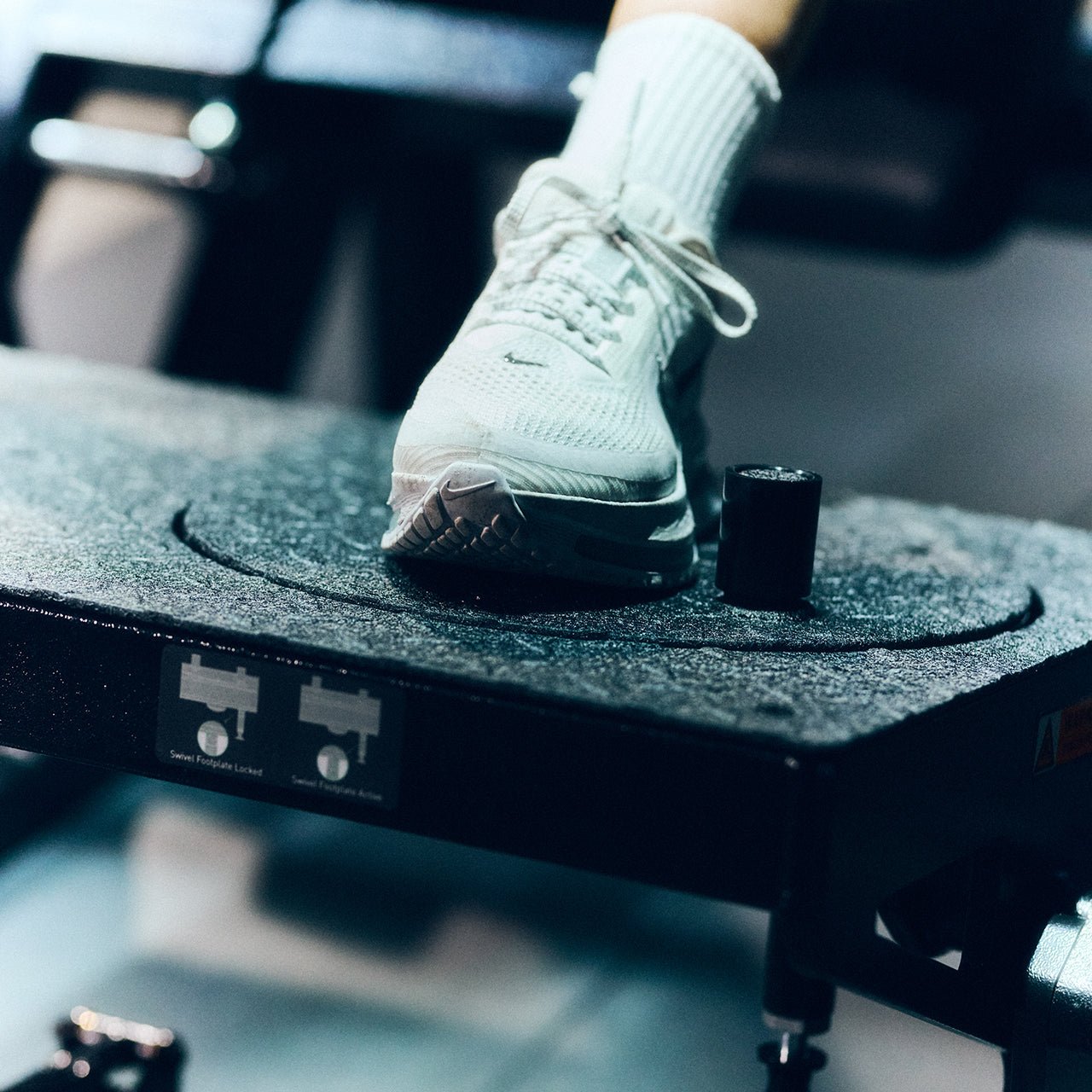 Close up of a footplate on a glute drive machine with a blurred background.