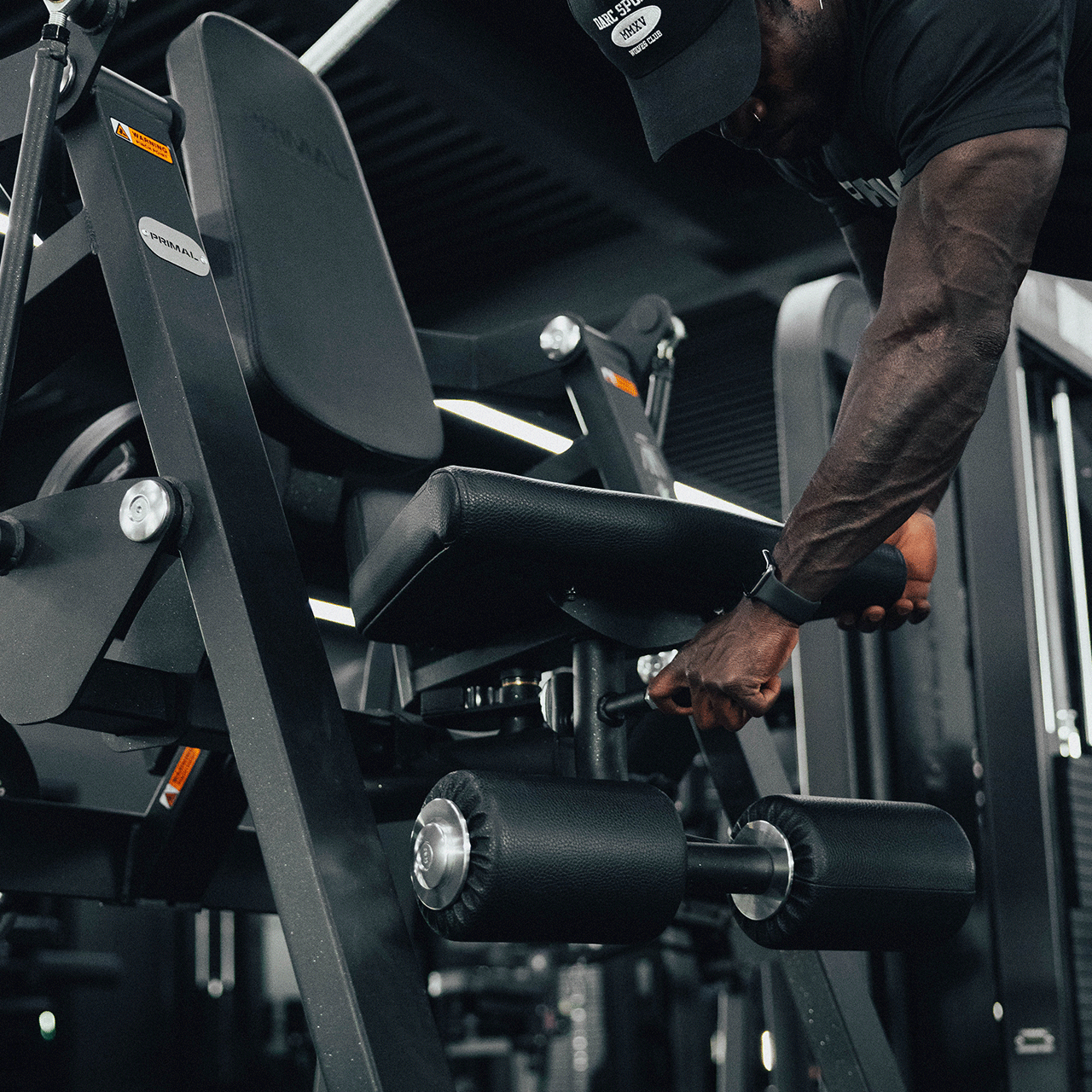 An athlete adjusting the angle of the seat on a plate loaded ab crunch machine.