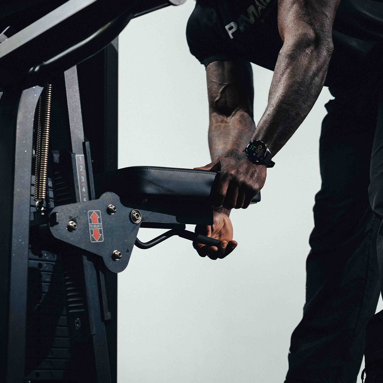 Person adjusting the seat height on a bicep curl machine. 