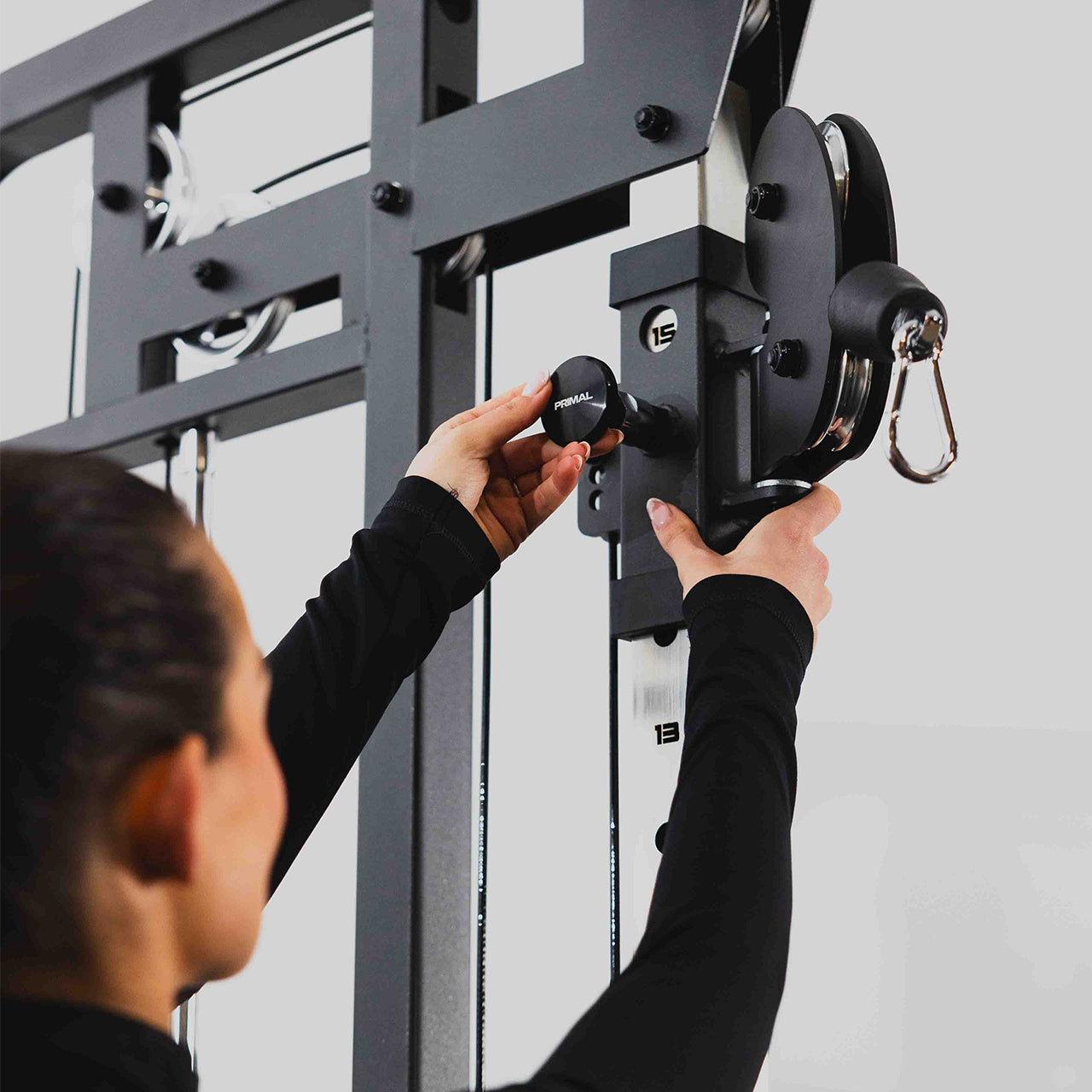 Person adjusting the height of the pulley on a dual cable machine.