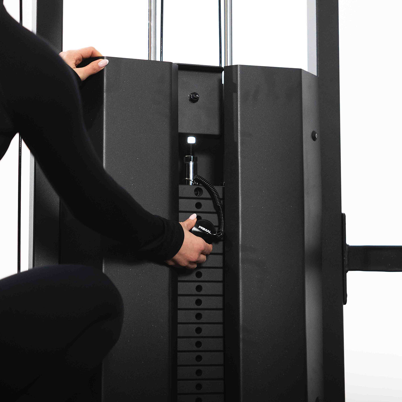 An athlete changing the weight resistance on a dual cable machine in a gym setting.
