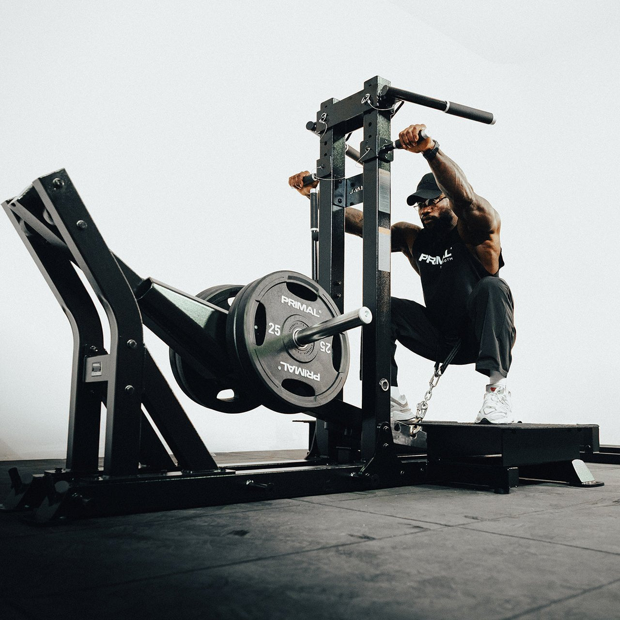 An athlete using a plate loaded belt squat machine in a gym.