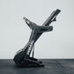 Black Primal folding treadmill on a grey floor with a white wall background