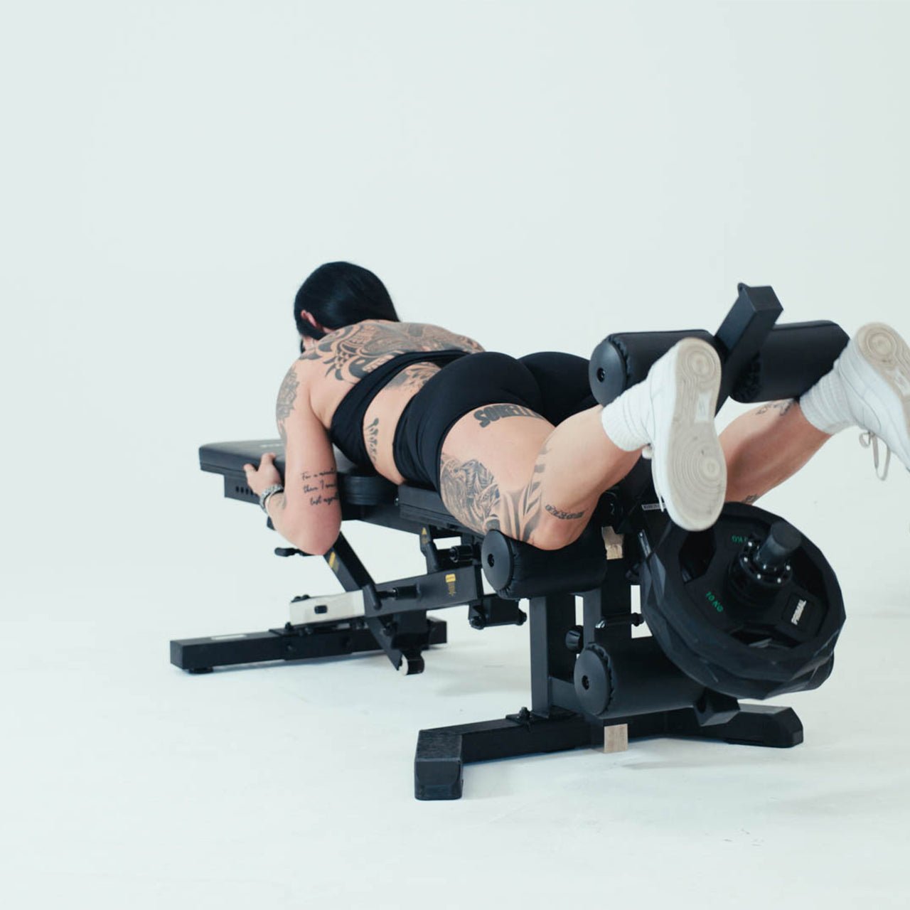 An athlete using a hamstring curl attachment on a weight bench.
