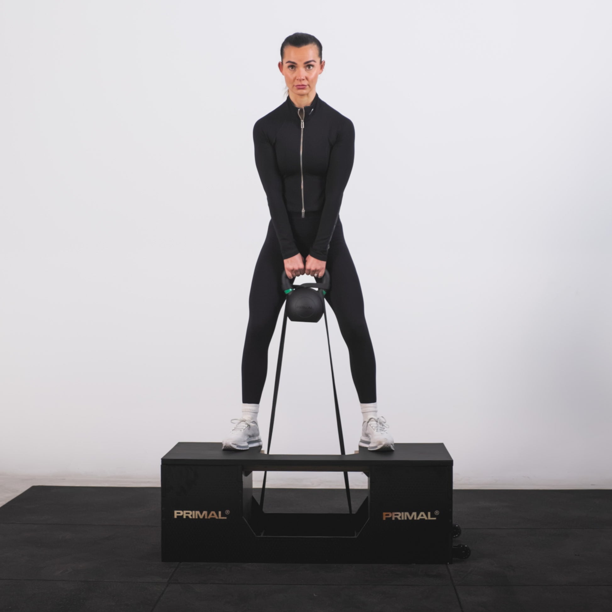 An athlete performing a squat with a kettlebell on a glute weight bench.