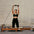 Woman exercising on a Pilates reformer machine against a brick wall.