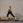 Woman in black athletic wear performing a yoga pose on a reformer against a brick wall.