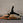 Person performing a Pilates exercise on a reformer machine against a brick wall.