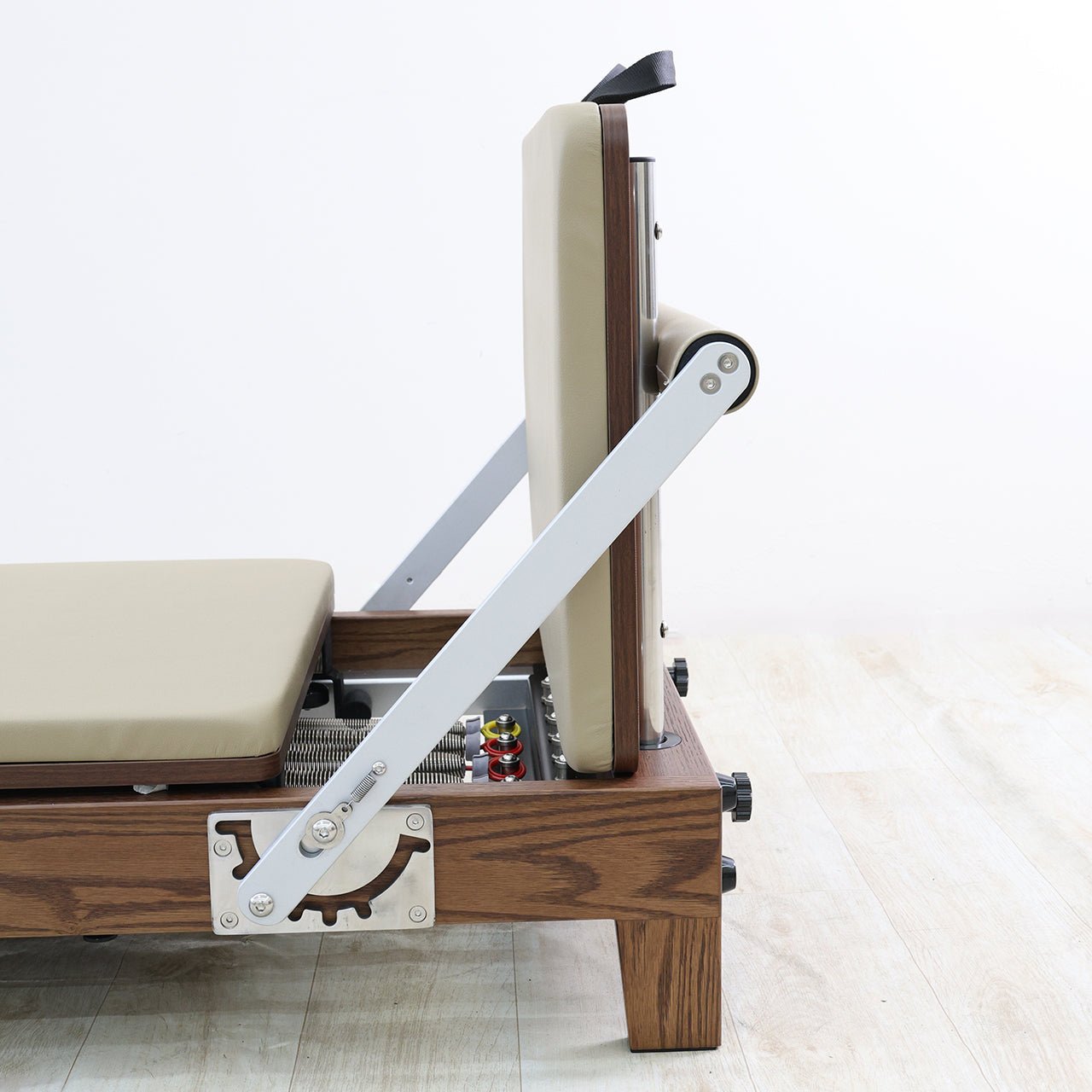 Wooden pilates reformer with beige cushion on a white background
