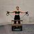 Woman exercising with Pilates reformer against a brick wall.