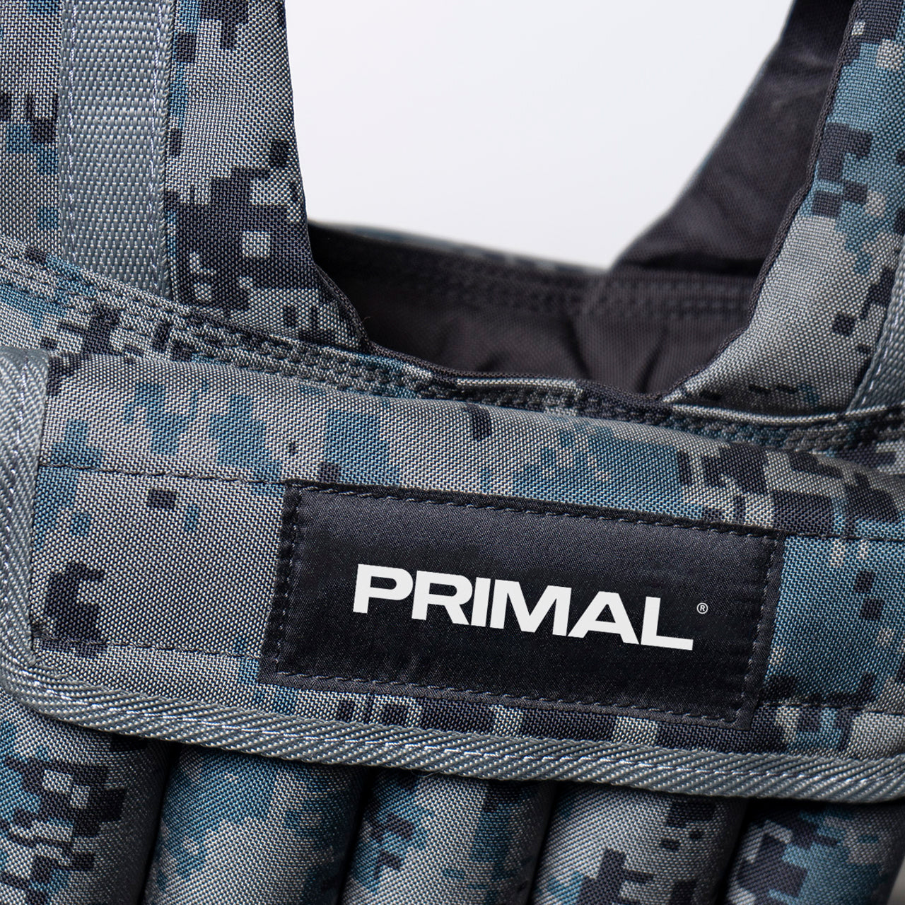 Close-up of a Primal brand label on a camouflage-patterned weighted vest.