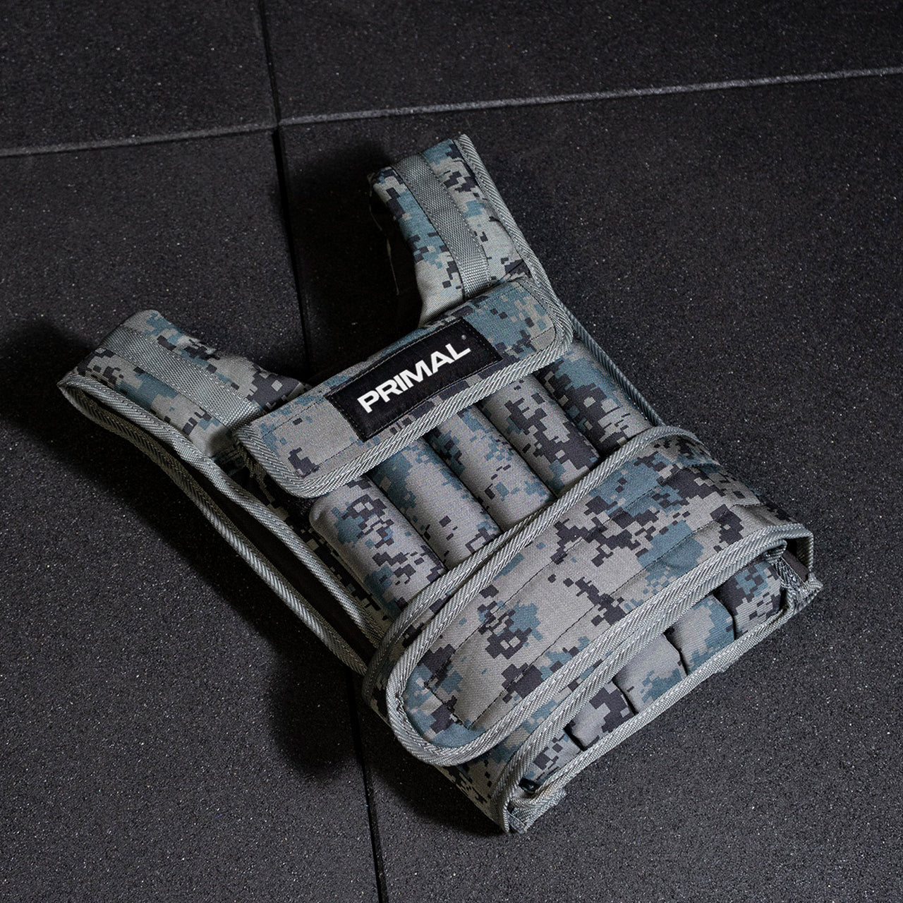 Digital camouflage weighted vest on a dark surface with 'Primal' branding.