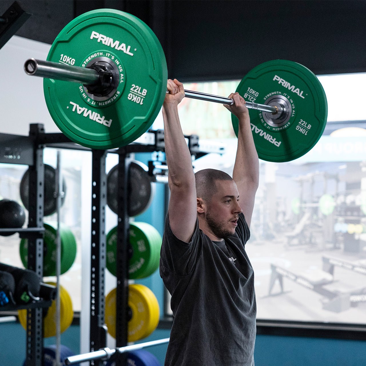 An athlete performing an overhead press with a barbell filled with bumpers plates.