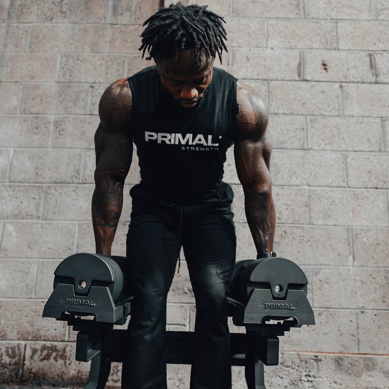 An athlete lifting a pair of 40kg adjustable dumbbells from a stand.