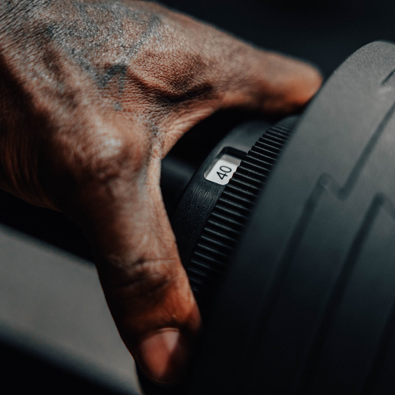 An athlete adjusting the weight level on an adjustable dumbbell.