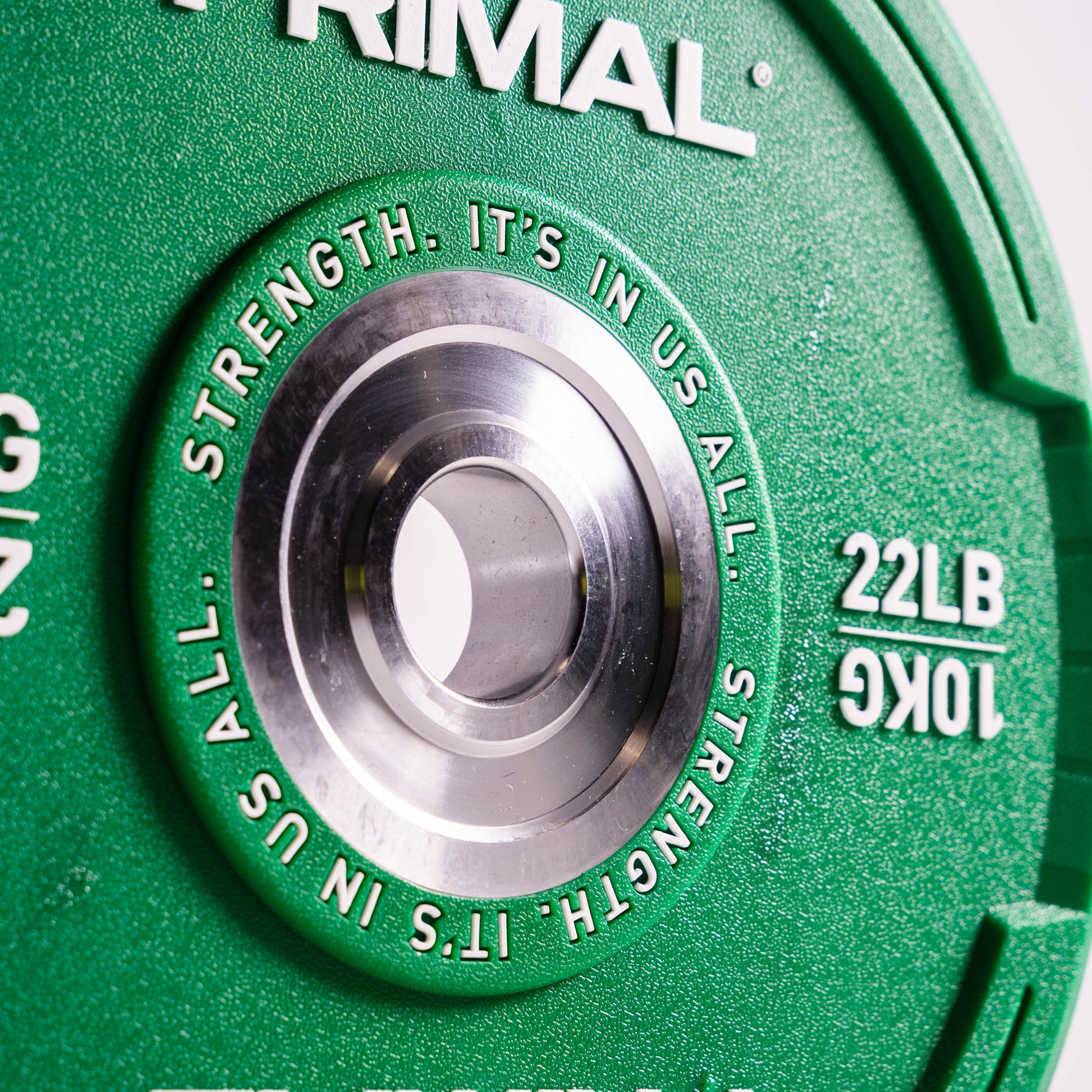 Close-up of a green weight plate with 'Primal' branding and weight measurement.