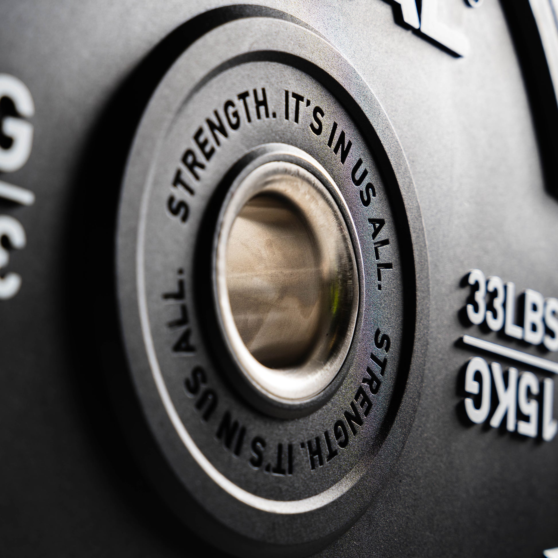 Close-up of a weight plate with motivational text and weight measurement.