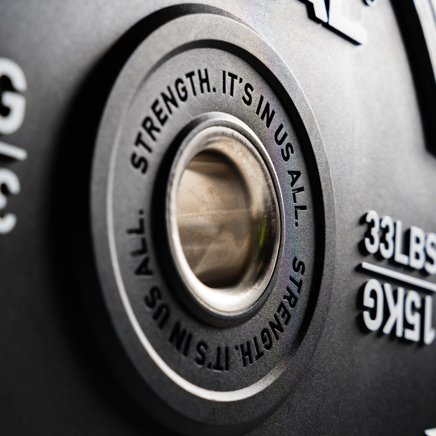 Close-up of a weight plate with motivational text and weight measurement.
