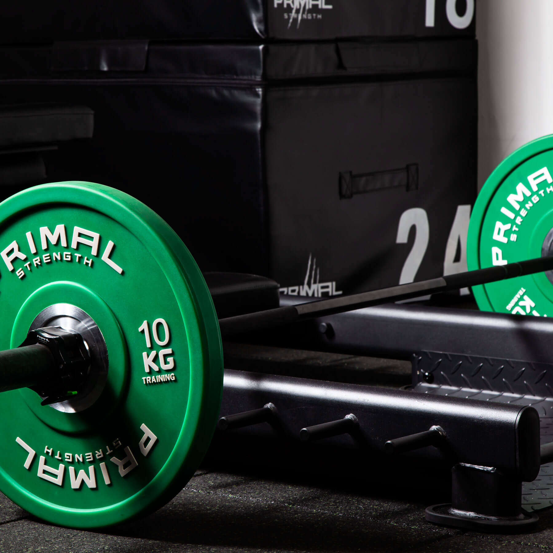 a barbell loaded with a pair of weight plates on a floor hip thrust bench