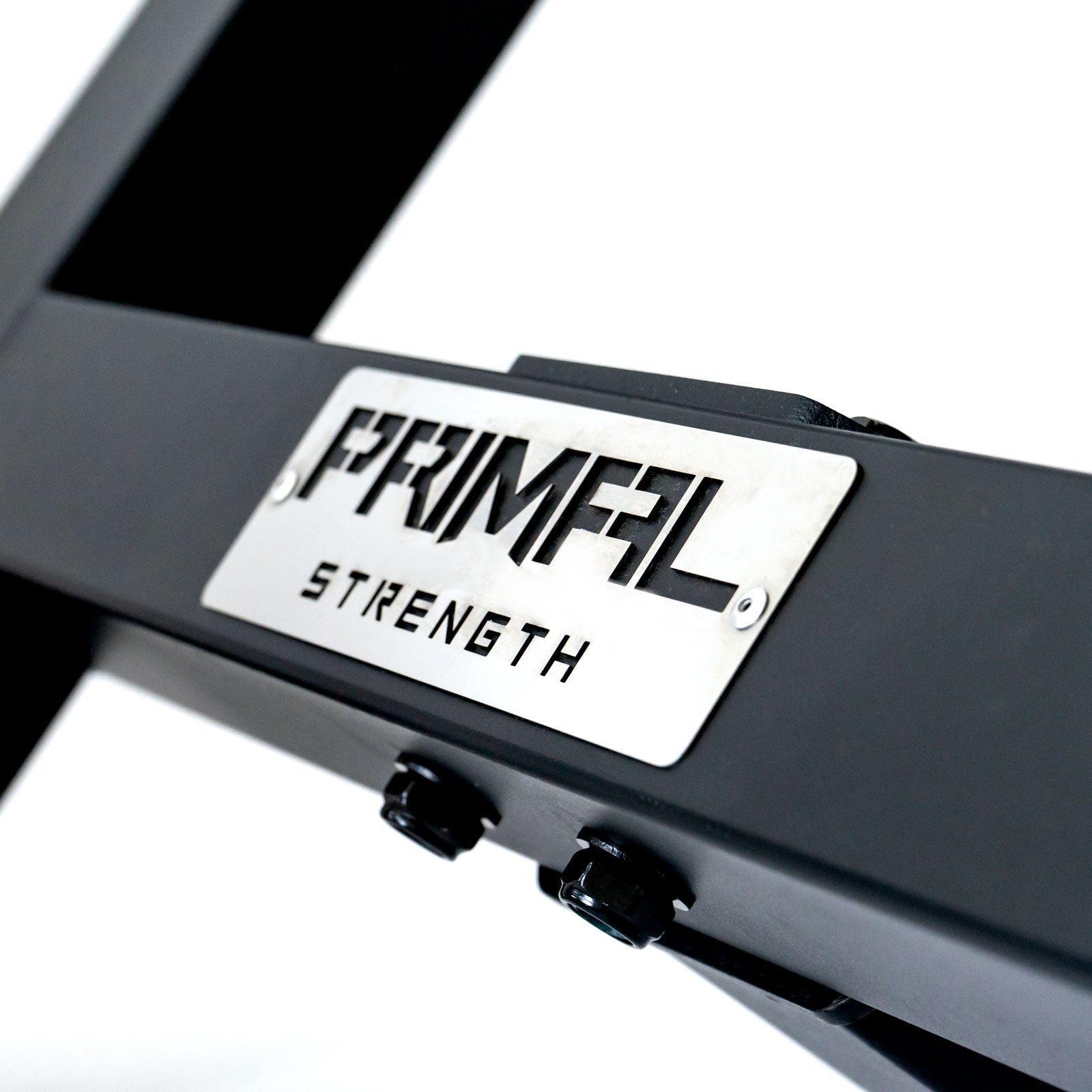 a metal plate with a lasered primal strength logo on a preacher curl bench