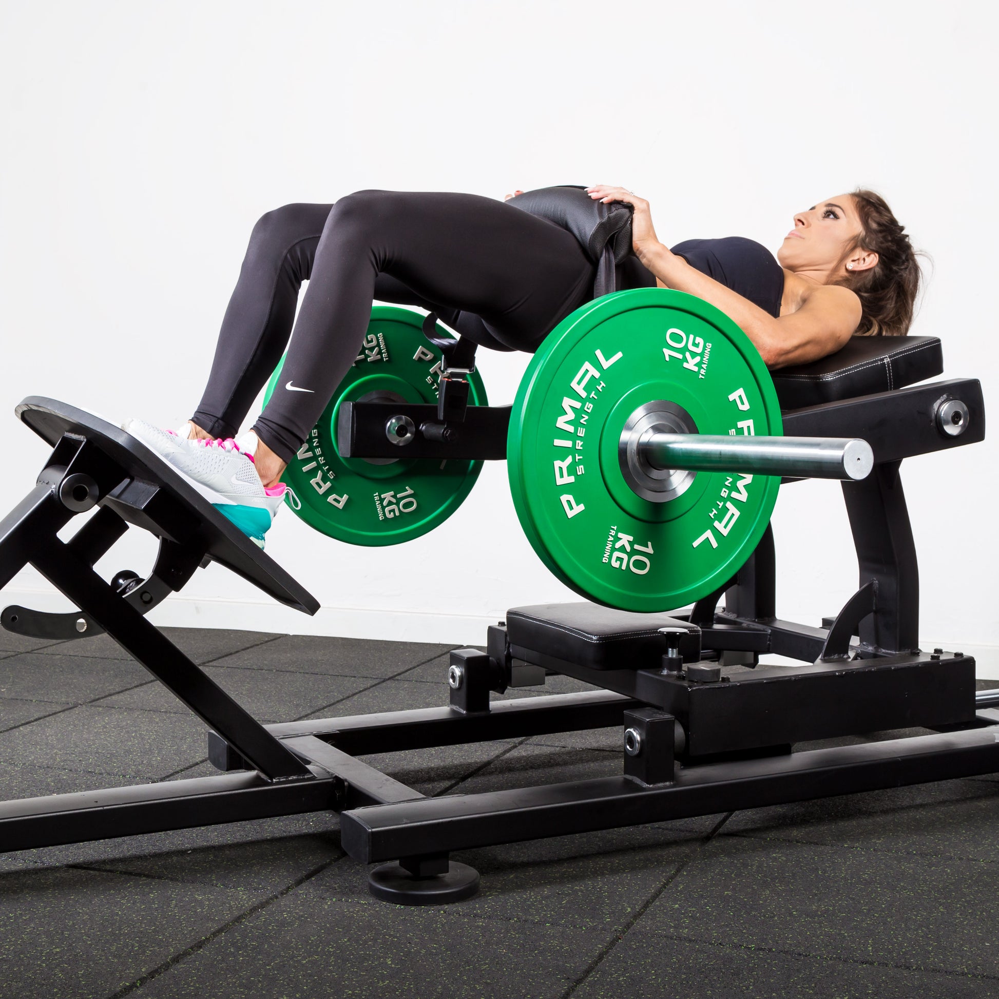 a woman performing hip thrusts on a plate loaded glute drive gym machine