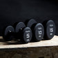 three single primal strength black urethane dumbbells on a wooden box