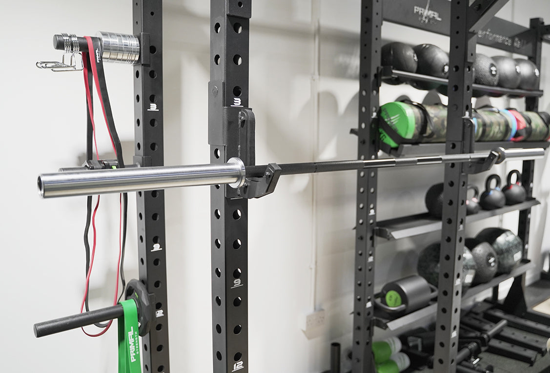 a silver olympic barbell on a rack with functional exercise equipment in the background