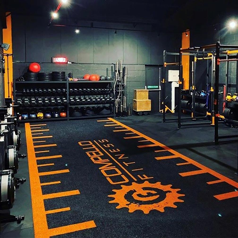 a custom compello fitness black and orange astro turf gym track