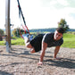 a man performing ab exercises with a suspension trainer in a park