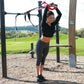 a woman exercising with a suspension trainer in a park